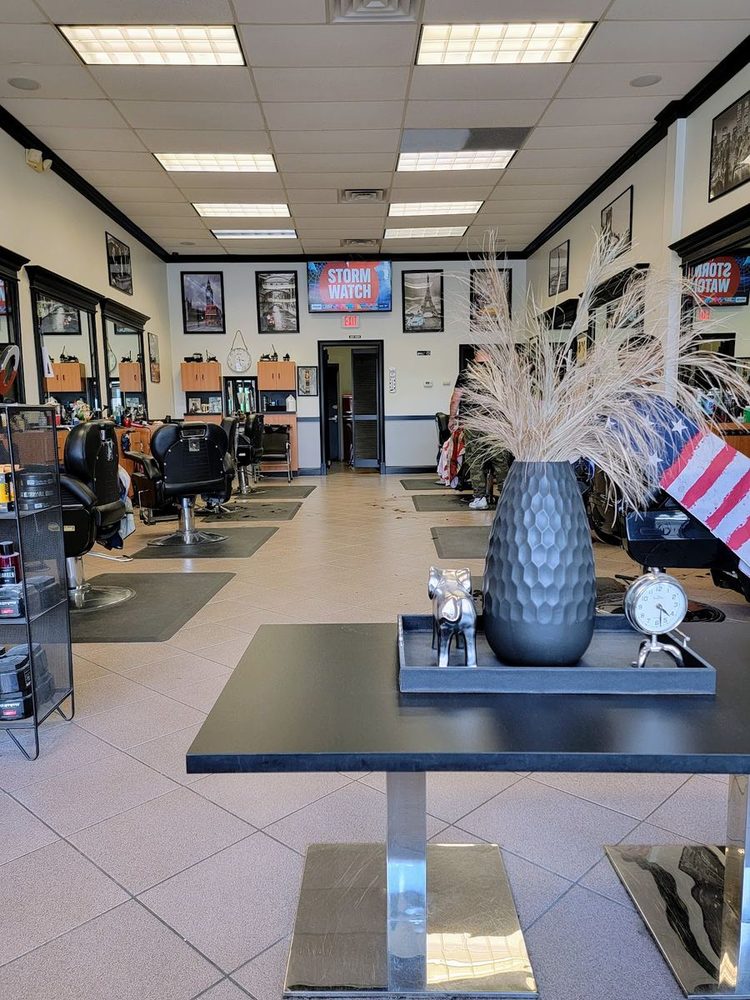 Inside the shop: a row of black barber chairs, grey walls and framed black-and-white photos.